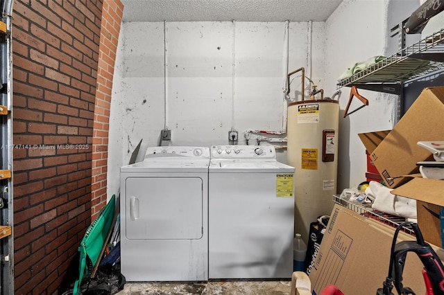 washroom featuring washing machine and dryer, water heater, a textured ceiling, and brick wall