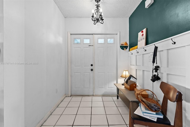 foyer entrance featuring a textured ceiling, a chandelier, and light tile patterned flooring