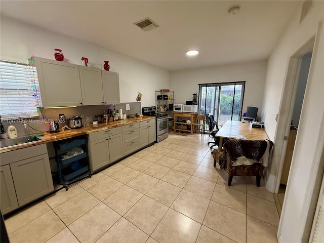 kitchen featuring stainless steel electric range, sink, tasteful backsplash, light tile patterned flooring, and wooden counters