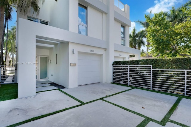 view of front facade with concrete driveway, an attached garage, and stucco siding