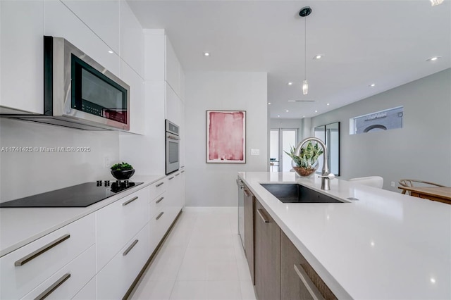 kitchen with pendant lighting, stainless steel appliances, light countertops, white cabinetry, and modern cabinets