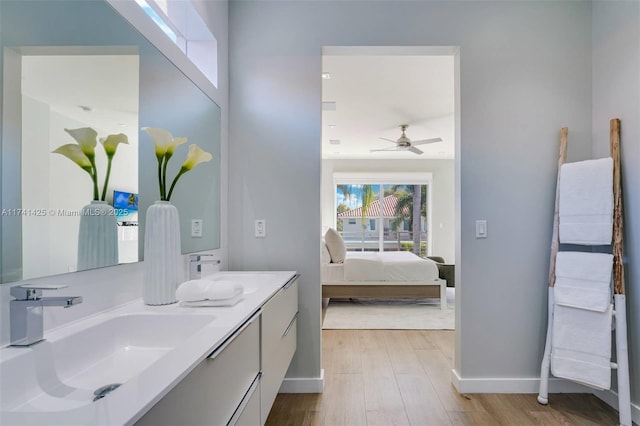 ensuite bathroom with a sink, double vanity, connected bathroom, and wood finished floors