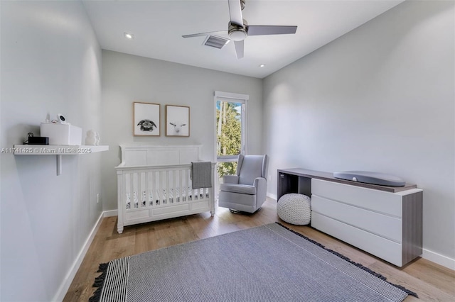 bedroom featuring light wood-style floors, visible vents, baseboards, and a ceiling fan