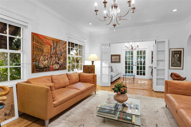 living room with light hardwood / wood-style floors, french doors, crown molding, and a notable chandelier