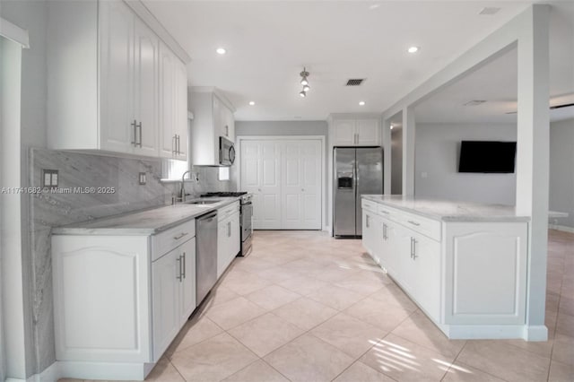 kitchen with appliances with stainless steel finishes, sink, light stone counters, white cabinets, and tasteful backsplash