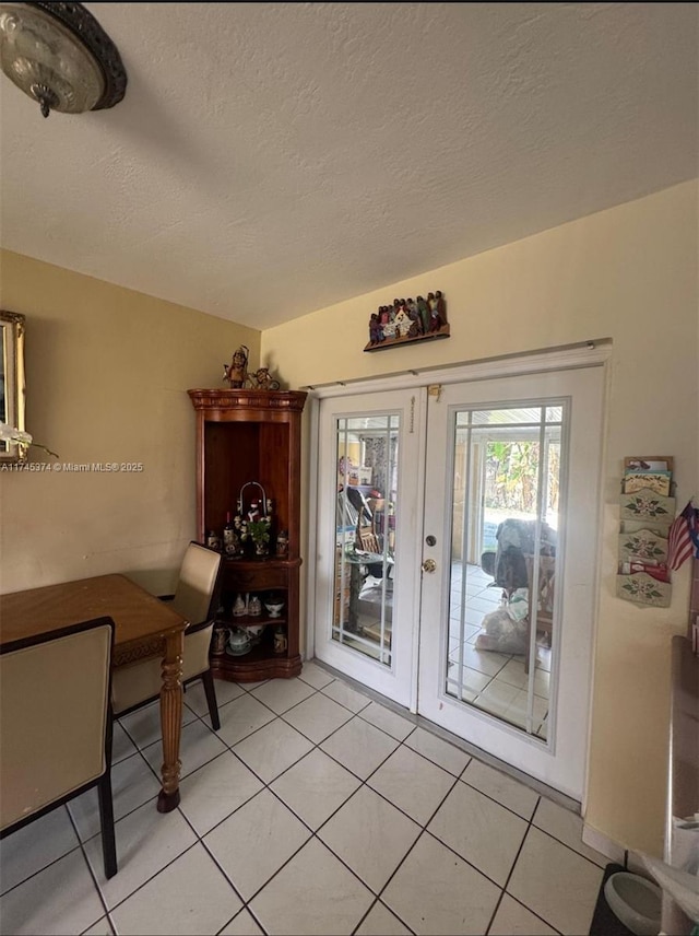 dining room featuring a textured ceiling, french doors, and light tile patterned floors