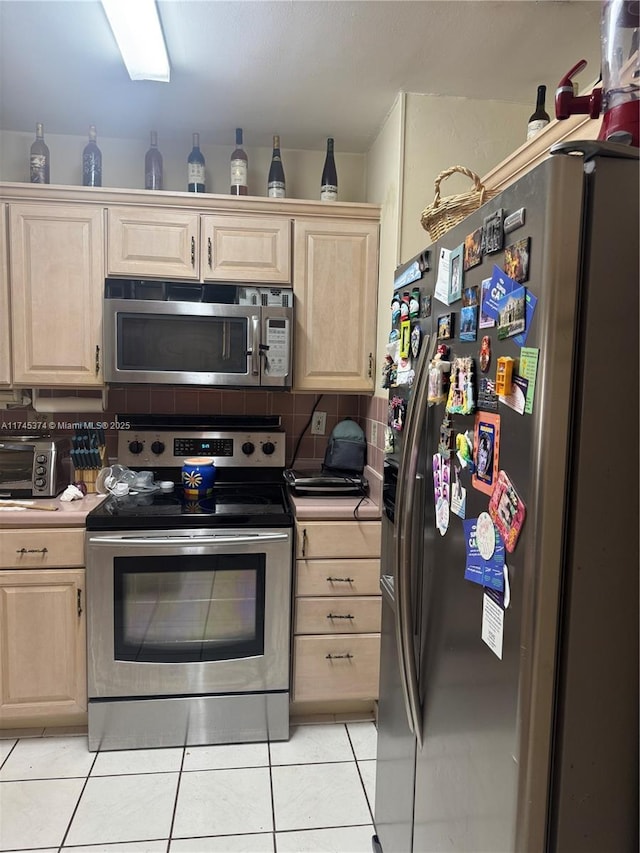 kitchen with appliances with stainless steel finishes, light brown cabinetry, light tile patterned floors, and decorative backsplash