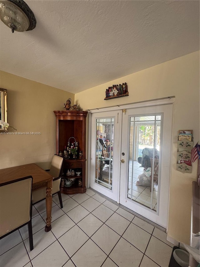 tiled dining area featuring french doors and a textured ceiling