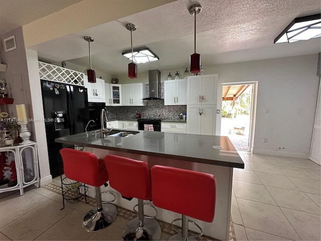 kitchen featuring hanging light fixtures, a breakfast bar, sink, white cabinets, and wall chimney exhaust hood