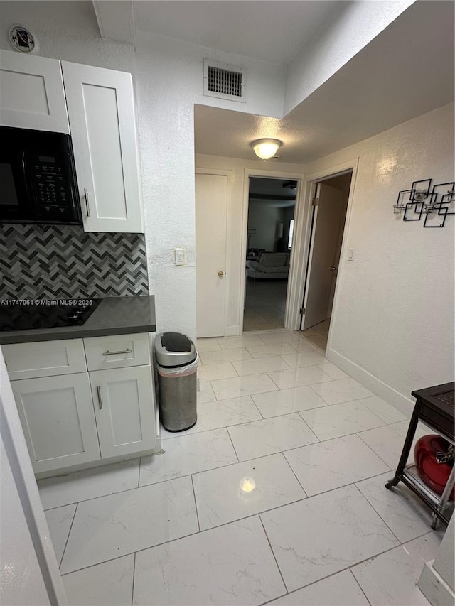 kitchen with white cabinetry, black appliances, and tasteful backsplash