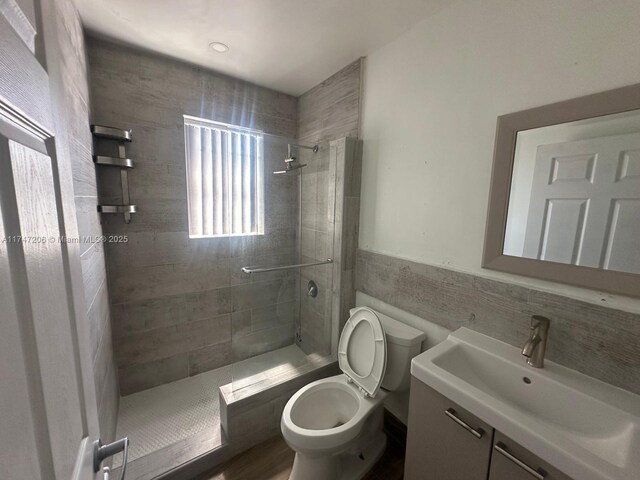 13926 SW 164th St, Miami, FL 33177 - full bathroom featuring a tile shower, toilet, tile walls, vanity, and a wainscoted wall