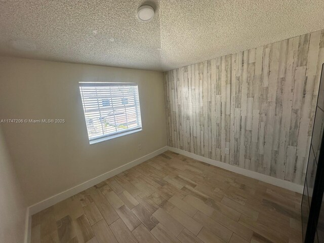 13926 SW 164th St, Miami, FL 33177 - empty room featuring a textured ceiling, wood finished floors, baseboards, and wooden walls