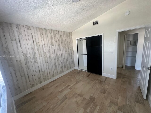 13926 SW 164th St, Miami, FL 33177 - unfurnished bedroom with wood finished floors, wood walls, vaulted ceiling, a textured ceiling, and a closet