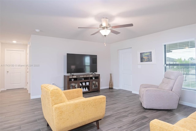 living area featuring ceiling fan, baseboards, and wood finished floors