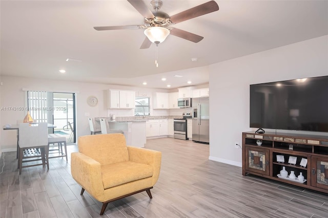 living area featuring ceiling fan, light wood finished floors, recessed lighting, and baseboards