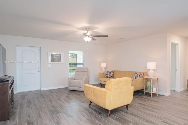 living area with a ceiling fan, wood finished floors, visible vents, and baseboards