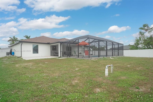 back of house featuring glass enclosure, a fenced backyard, a yard, stucco siding, and a patio area