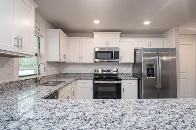 kitchen with stainless steel appliances, backsplash, a sink, and light stone countertops