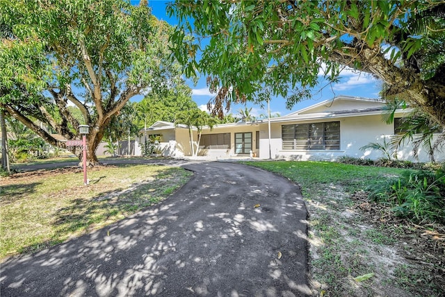 ranch-style home featuring stucco siding, driveway, and a front yard