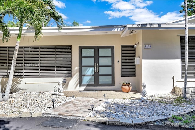 view of exterior entry with french doors and stucco siding