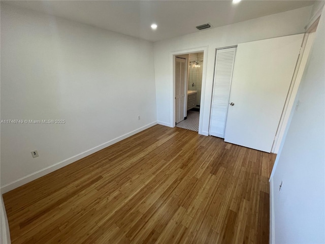 unfurnished bedroom featuring hardwood / wood-style flooring and ensuite bathroom