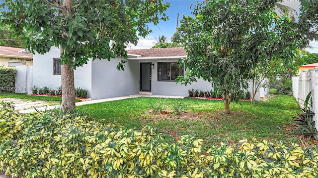 view of front of property featuring a front yard, fence, and stucco siding