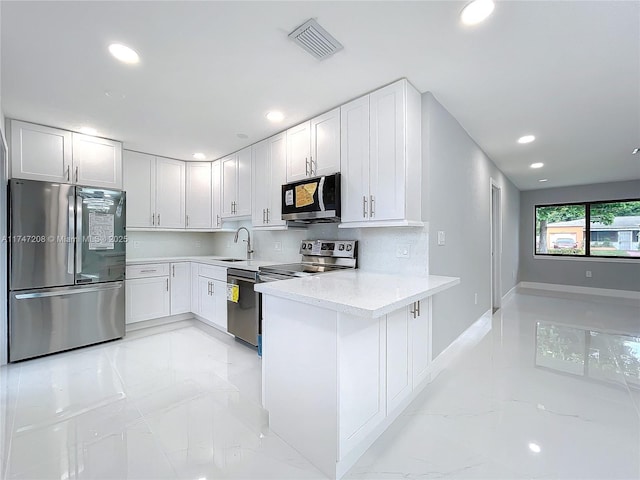 kitchen with stainless steel appliances, a peninsula, visible vents, marble finish floor, and backsplash