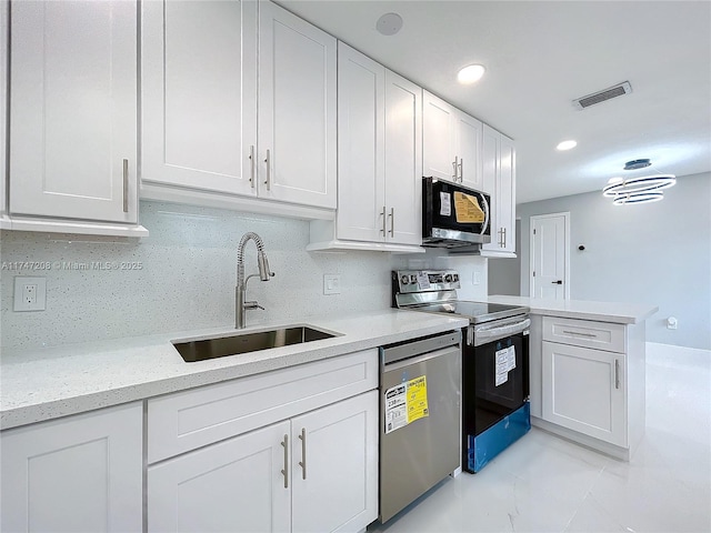 kitchen with visible vents, appliances with stainless steel finishes, white cabinets, a sink, and a peninsula