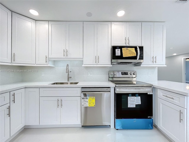 kitchen with light countertops, decorative backsplash, appliances with stainless steel finishes, white cabinets, and a sink