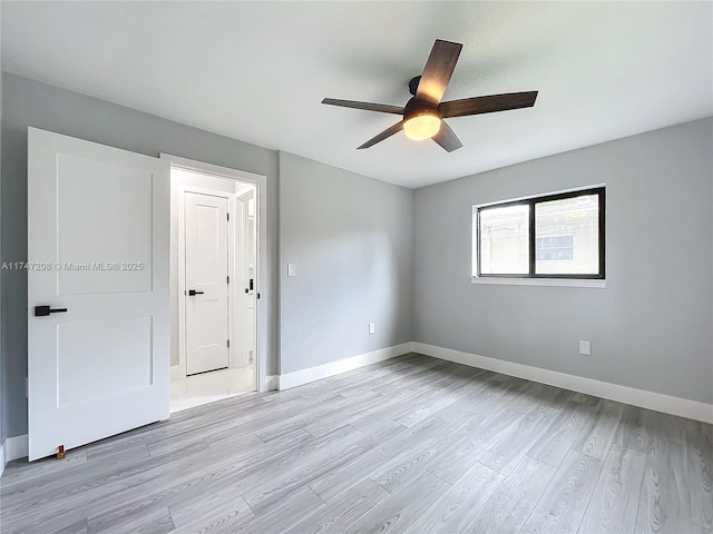 empty room featuring light wood-style floors, baseboards, and a ceiling fan