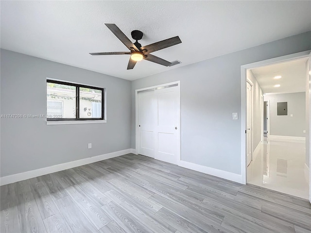 unfurnished bedroom with electric panel, baseboards, ceiling fan, wood finished floors, and a closet