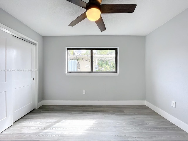 unfurnished bedroom with a textured ceiling, ceiling fan, baseboards, a closet, and light wood-type flooring