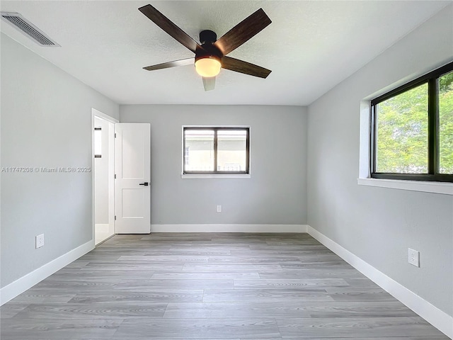 unfurnished room featuring plenty of natural light, visible vents, and baseboards