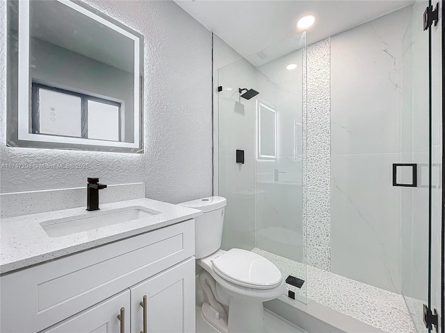 full bathroom featuring a stall shower, a textured wall, vanity, and toilet