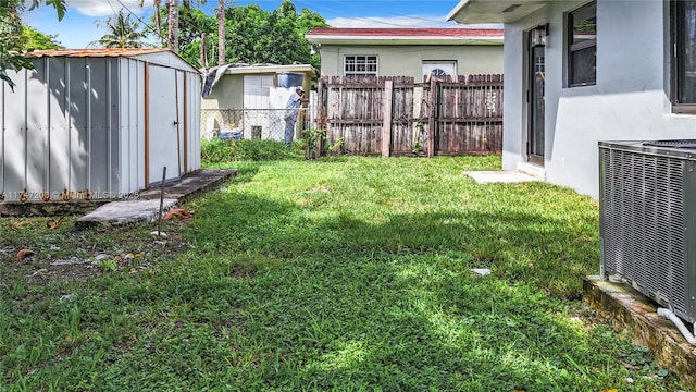 view of yard with an outdoor structure, fence, a storage shed, and central AC unit