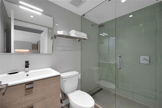 bathroom featuring an enclosed shower, toilet, tile walls, backsplash, and vanity