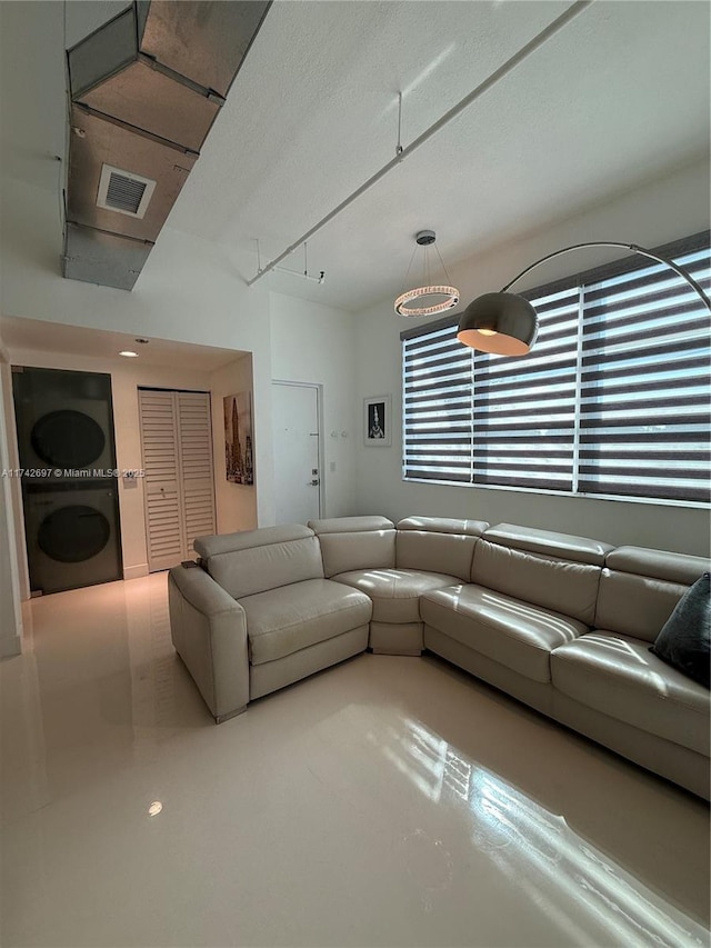 living room with concrete floors and stacked washing maching and dryer