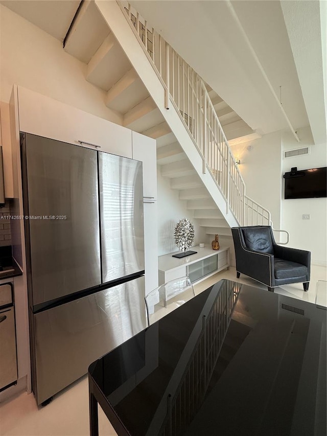 kitchen with stainless steel refrigerator and white cabinets