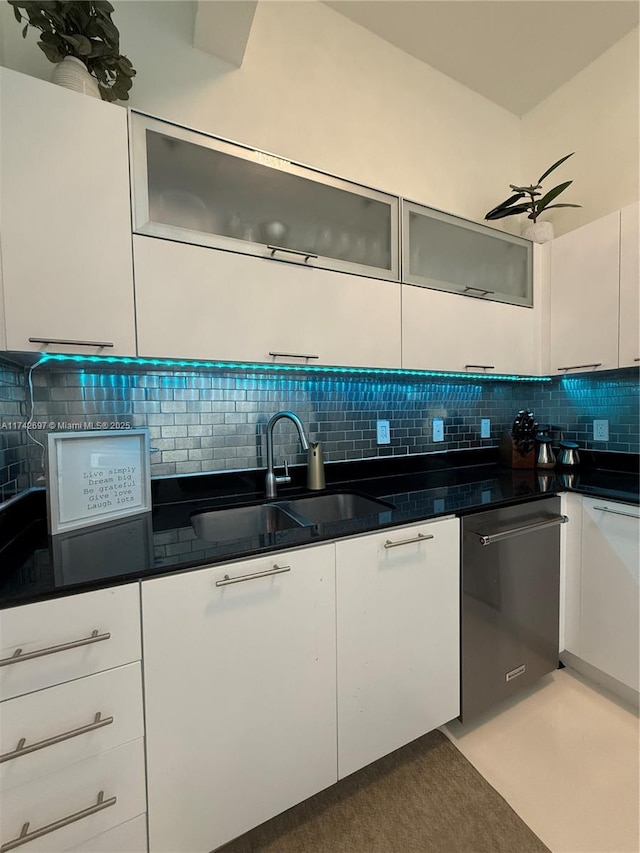 kitchen featuring sink, backsplash, white cabinets, and dishwashing machine