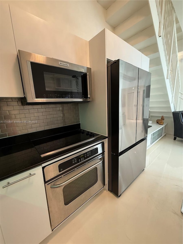 kitchen with white cabinetry, backsplash, and stainless steel appliances