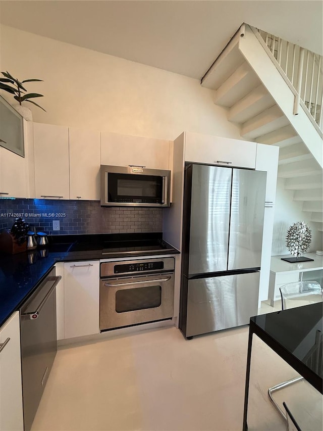 kitchen with appliances with stainless steel finishes, white cabinetry, and backsplash