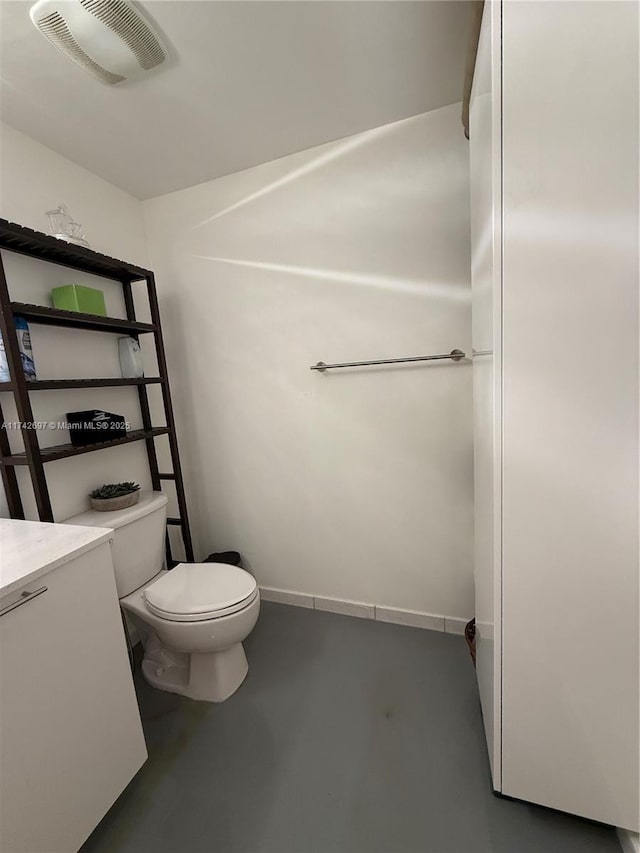 bathroom with concrete floors, vanity, and toilet