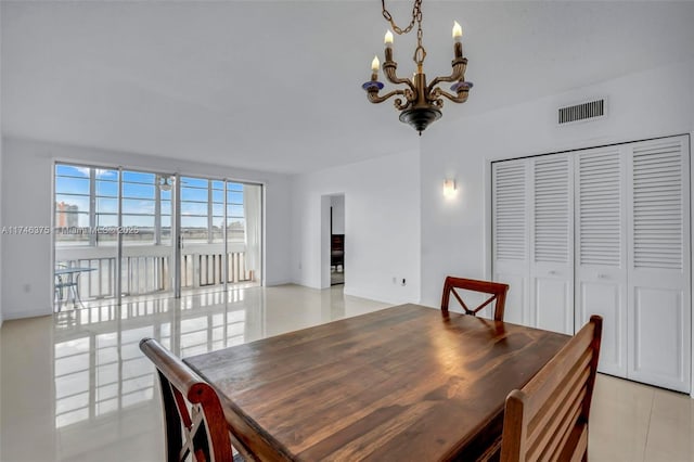 dining space with a water view, light tile patterned flooring, and a notable chandelier