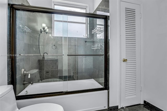 bathroom with toilet and shower / bath combination with glass door