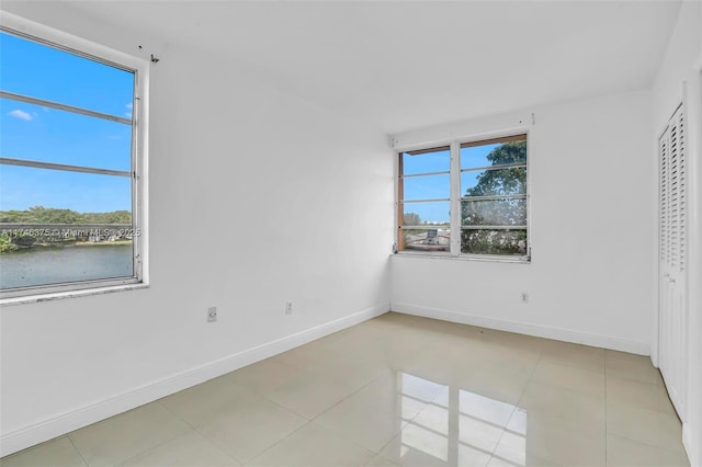 empty room featuring a water view and light tile patterned floors