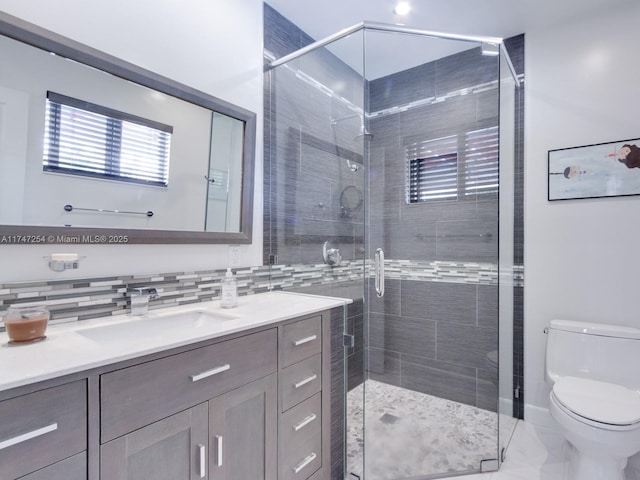 bathroom with vanity, tasteful backsplash, a shower with door, and toilet