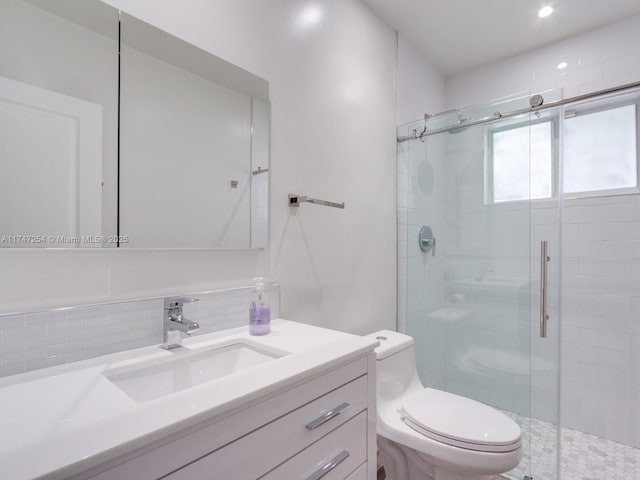 bathroom featuring toilet, vanity, and a shower with shower door