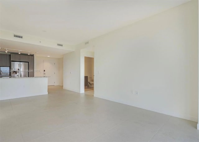 unfurnished living room featuring track lighting and light tile patterned floors