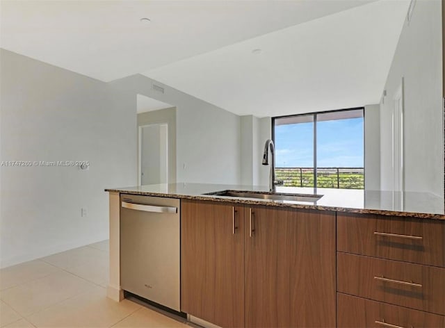 kitchen with light tile patterned floors, dishwasher, dark stone counters, and sink