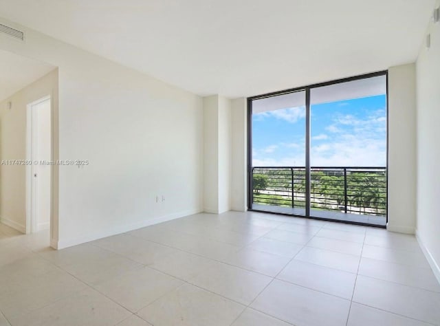 unfurnished room with expansive windows, light tile patterned floors, and baseboards